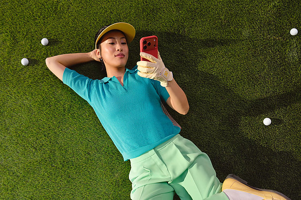 Liegende Frau mit Handy auf einem Golfplatz